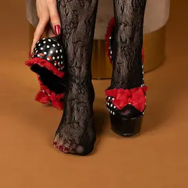 Füsse in schwarzen Spitzenstrümpfen mit rot-schwarzen High Heels, einen getragen und den anderen in der Hand gehalten - Fussfetisch Zürich